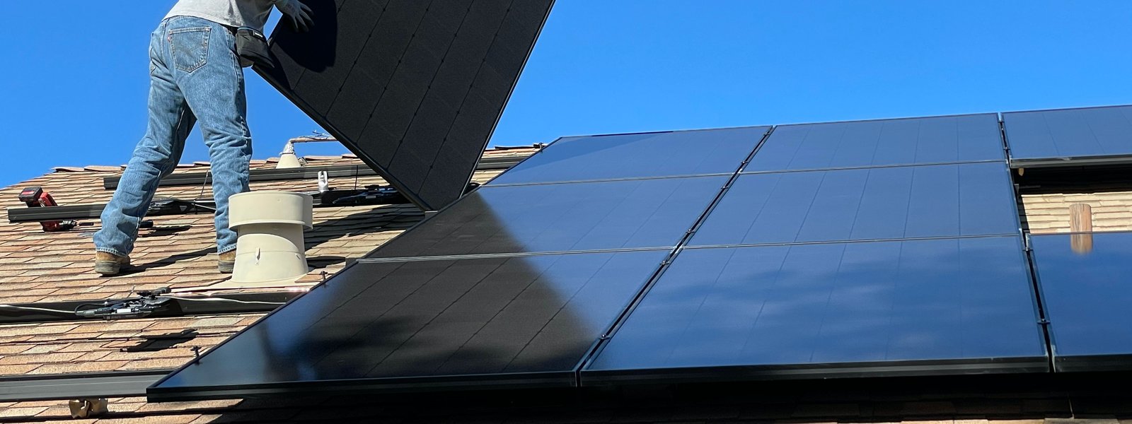 Worker installing solar panel on roof